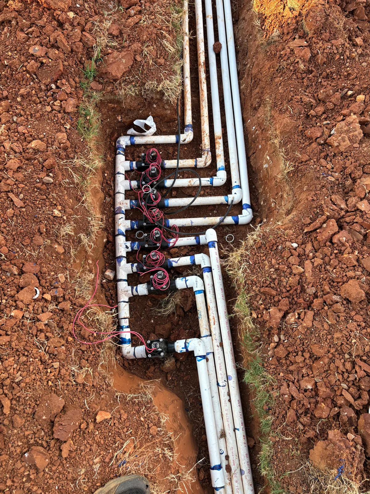 Irrigation piping, wiring and a valve manifold exposed for inspection
